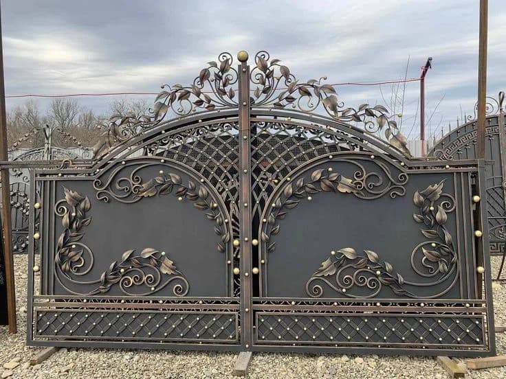 Ornamental double gate with an arched top and hand-shaped leaf and scroll details