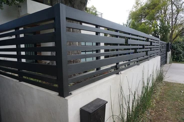 Black horizontal slat metal fence mounted above a concrete perimeter wall