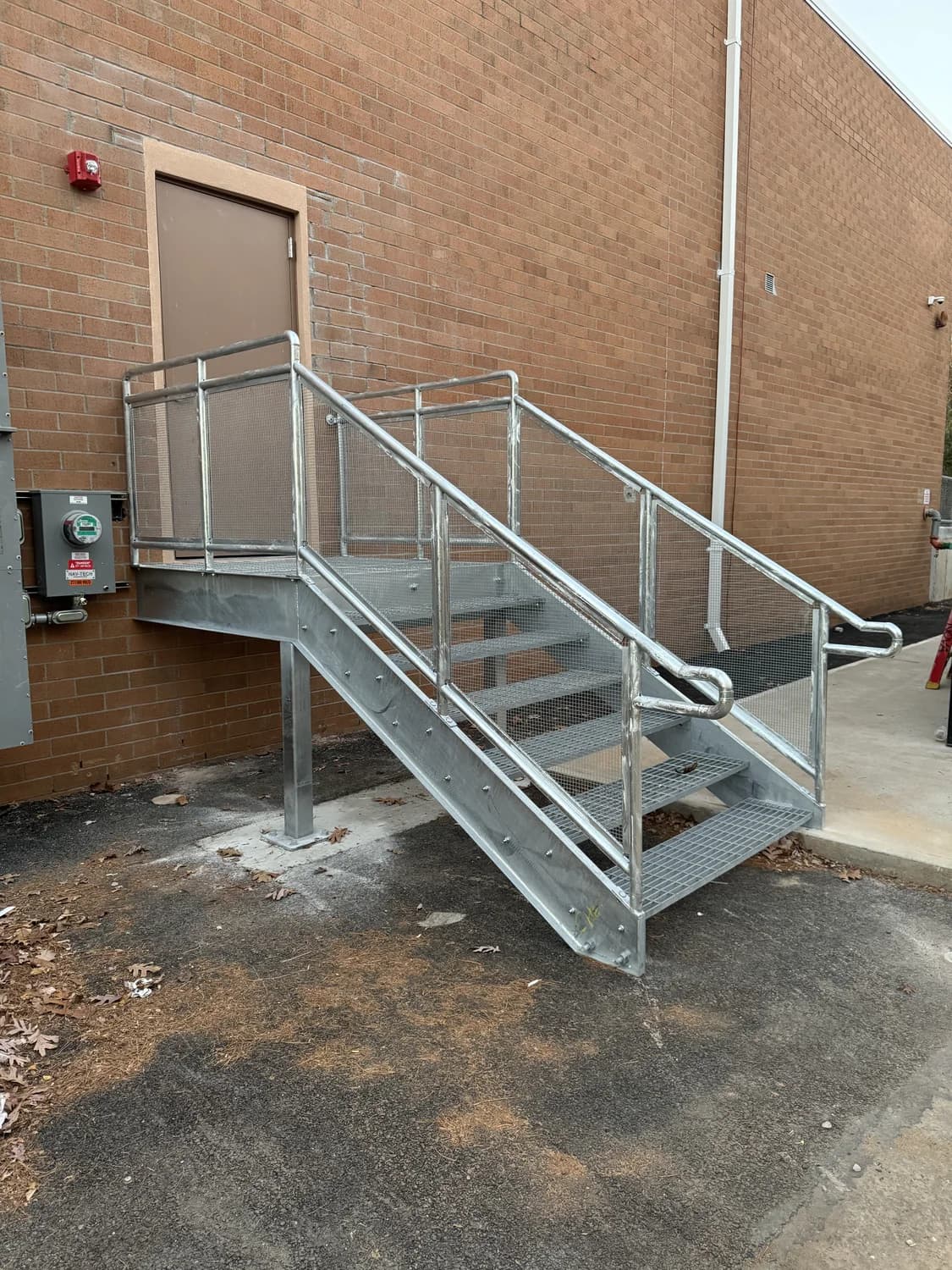 IronCore exterior metal staircase, landing, and handrails alongside a brick building
